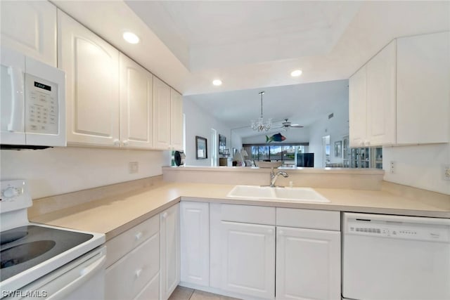 kitchen with kitchen peninsula, white appliances, ceiling fan, sink, and white cabinetry