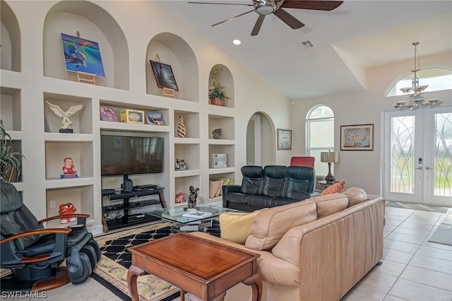 tiled living room featuring built in shelves, ceiling fan, a towering ceiling, and french doors