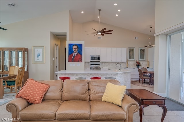 tiled living room featuring ceiling fan, sink, and high vaulted ceiling