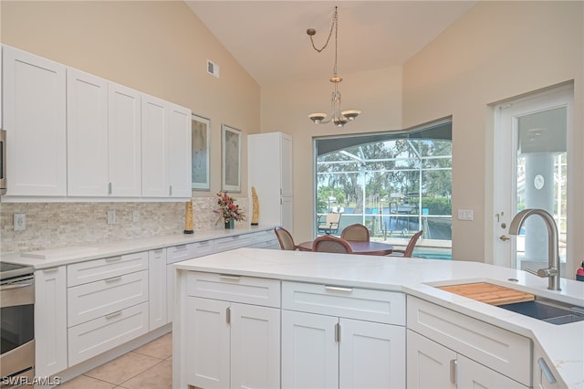 kitchen featuring white cabinets, an inviting chandelier, vaulted ceiling, and stainless steel stove