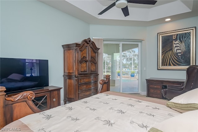 bedroom with access to outside, ceiling fan, and a tray ceiling