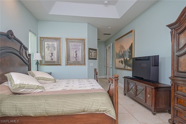 bedroom with light tile patterned flooring and a tray ceiling