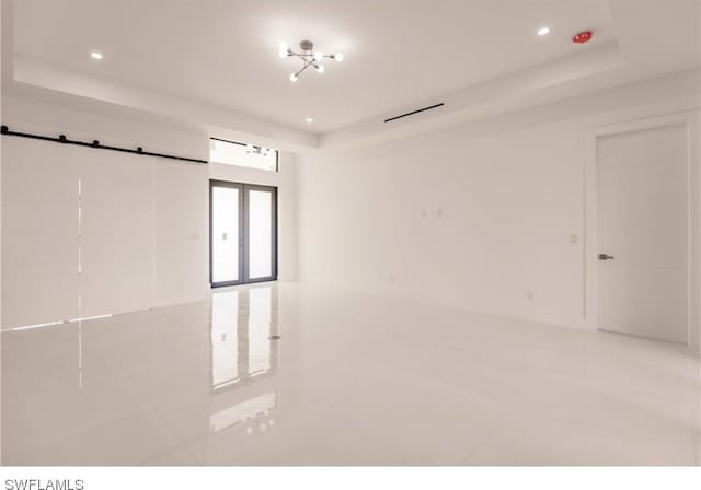 unfurnished room featuring a raised ceiling and light tile floors