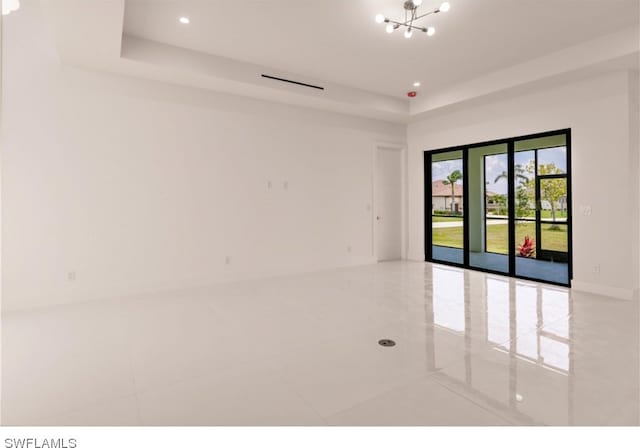 unfurnished room with a raised ceiling, light tile flooring, and a chandelier