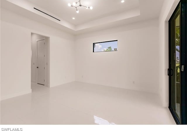 unfurnished room featuring a chandelier, light tile flooring, and a tray ceiling