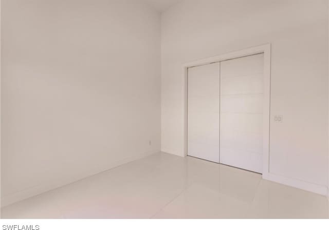 unfurnished bedroom featuring light tile flooring and a closet