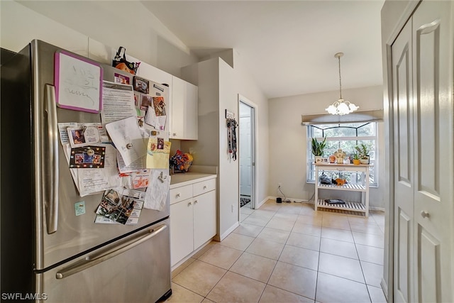 kitchen featuring pendant lighting, light tile floors, a chandelier, stainless steel refrigerator, and white cabinetry