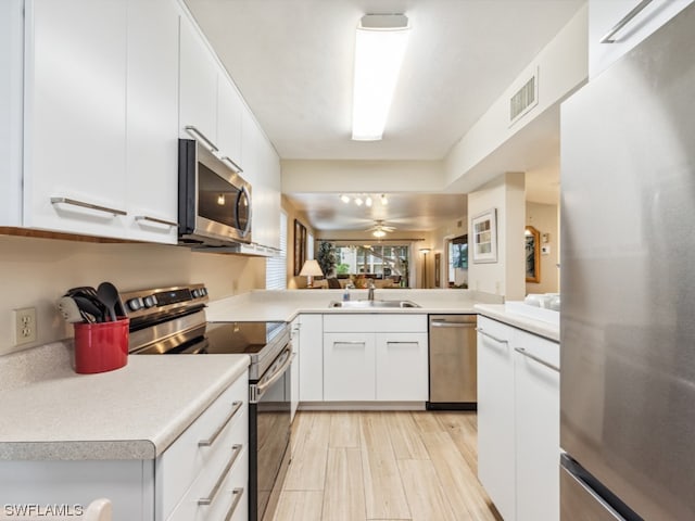 kitchen featuring stainless steel appliances, white cabinets, ceiling fan, and sink