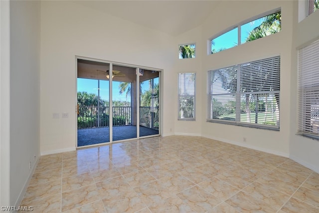 empty room with light tile floors, ceiling fan, and a towering ceiling