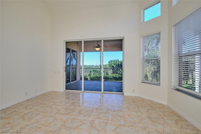 tiled spare room featuring a high ceiling, ceiling fan, and a wealth of natural light