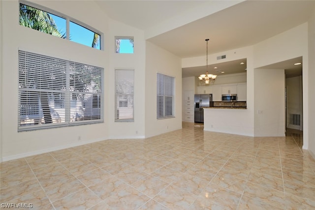 unfurnished living room with light tile floors and an inviting chandelier