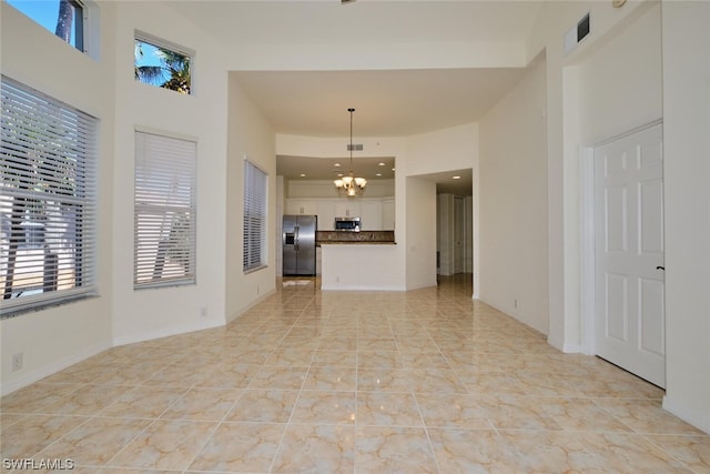 unfurnished living room with a notable chandelier and light tile floors