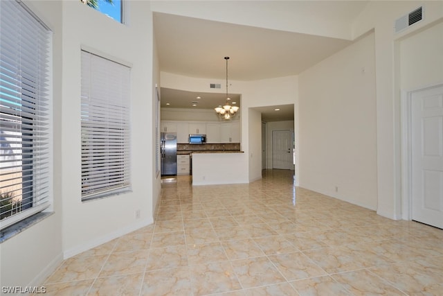 unfurnished living room with an inviting chandelier and light tile floors