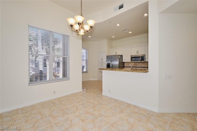 kitchen featuring light tile floors, a notable chandelier, appliances with stainless steel finishes, white cabinetry, and hanging light fixtures