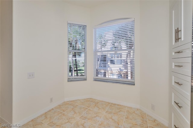 spare room featuring plenty of natural light and light tile floors