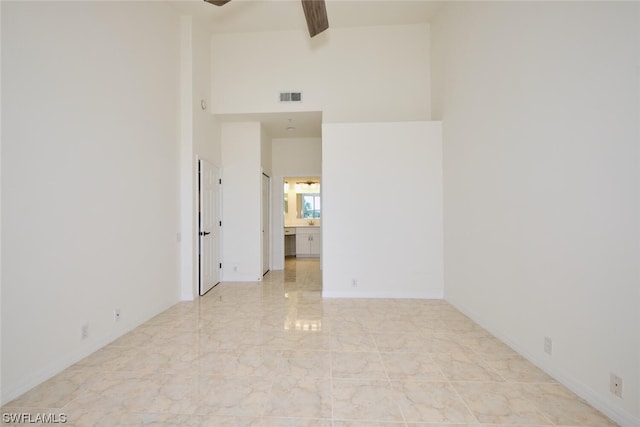 tiled empty room featuring a high ceiling, ceiling fan, and beam ceiling