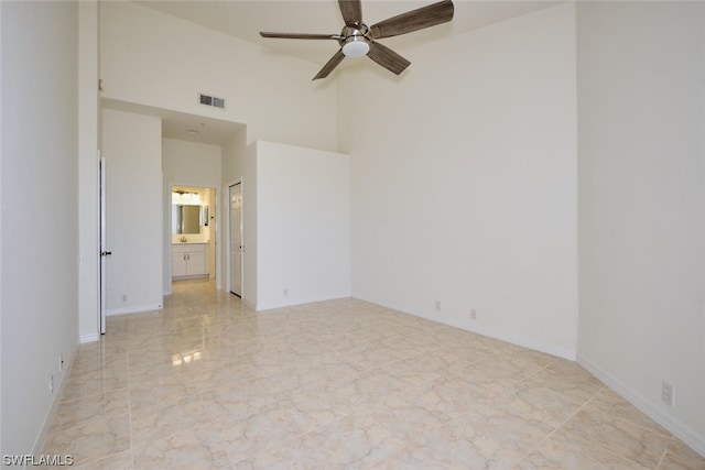 unfurnished bedroom featuring light tile floors, ceiling fan, ensuite bathroom, and a towering ceiling