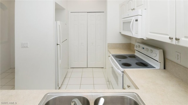 kitchen featuring white cabinetry, light tile patterned floors, white appliances, and sink