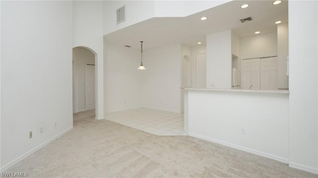 carpeted spare room with a towering ceiling