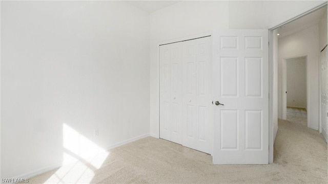 unfurnished bedroom featuring light carpet and a closet