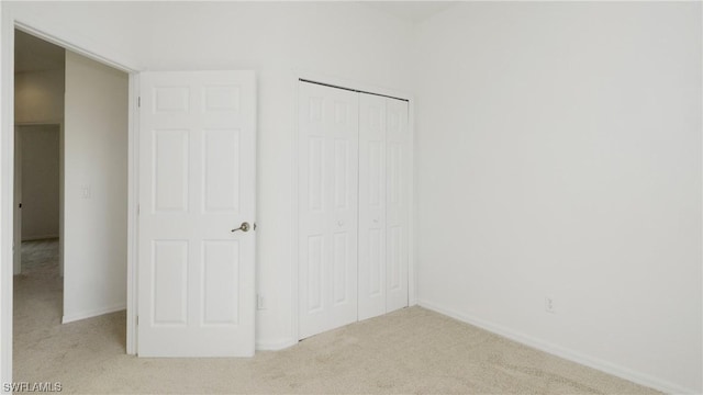 unfurnished bedroom with light colored carpet and a closet