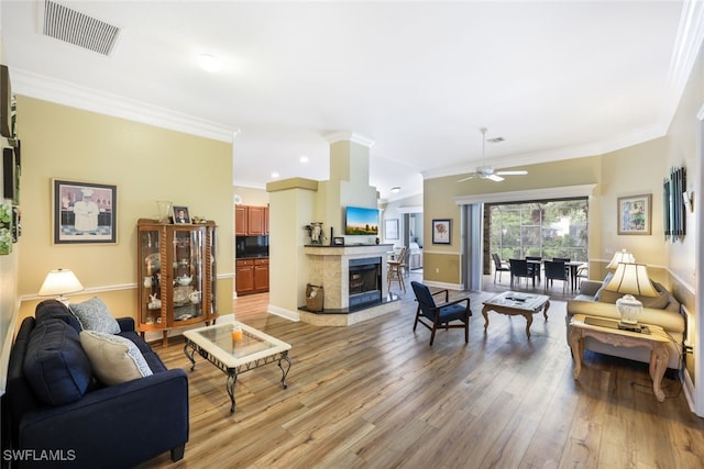 living room with ceiling fan, light wood-type flooring, and ornamental molding