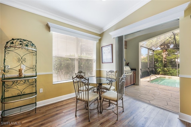 dining room featuring hardwood / wood-style flooring, vaulted ceiling, and ornamental molding