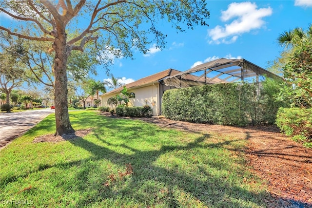 view of side of property with a lawn and glass enclosure