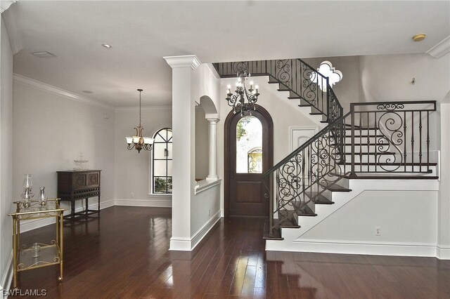 entrance foyer featuring a chandelier, dark hardwood / wood-style flooring, ornate columns, and crown molding