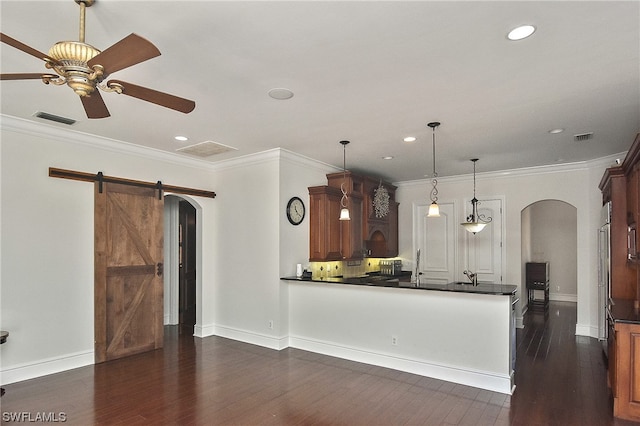 kitchen featuring a barn door, decorative light fixtures, ceiling fan, and crown molding