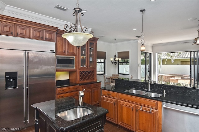 kitchen featuring built in appliances, a kitchen island, dark stone countertops, and sink