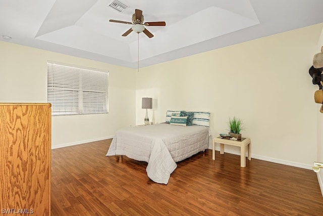 bedroom with a tray ceiling, ceiling fan, and dark hardwood / wood-style floors