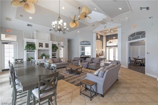 tiled living room featuring plenty of natural light and ceiling fan with notable chandelier