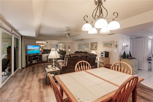 dining room featuring light hardwood / wood-style floors and ceiling fan with notable chandelier