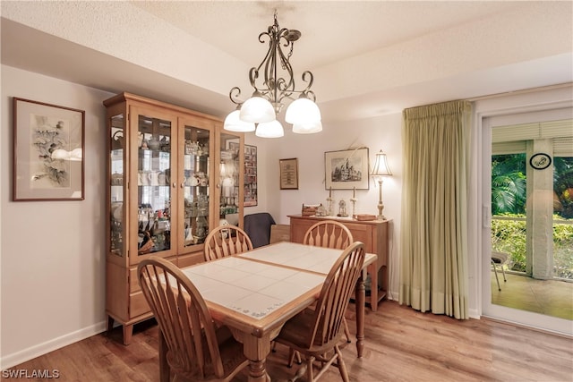 dining space with a notable chandelier, a textured ceiling, and light wood-type flooring