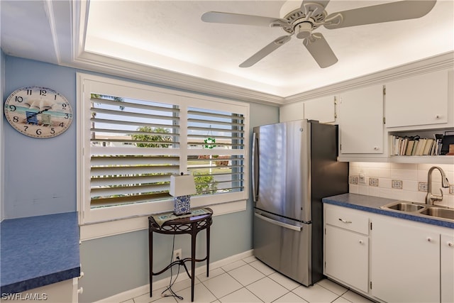 kitchen with sink, a raised ceiling, stainless steel refrigerator, tasteful backsplash, and white cabinetry