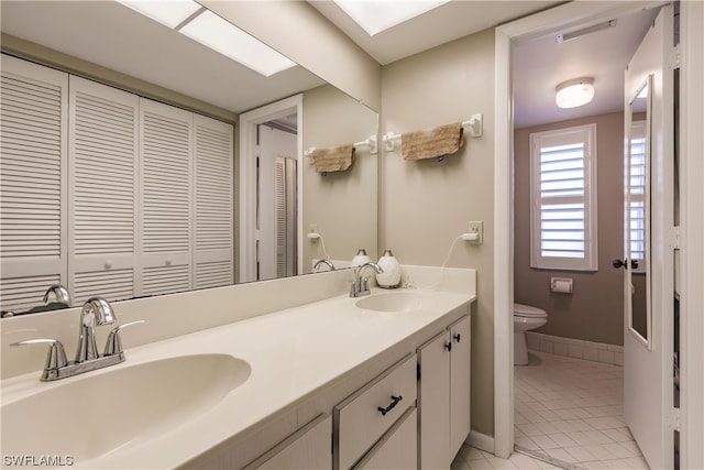 bathroom featuring toilet, double vanity, and tile floors