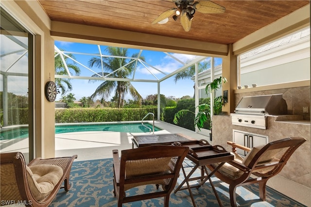 view of pool featuring exterior kitchen, glass enclosure, a grill, a patio, and ceiling fan