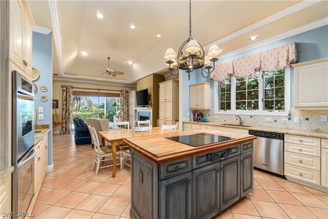 kitchen with a center island, appliances with stainless steel finishes, hanging light fixtures, sink, and a tray ceiling