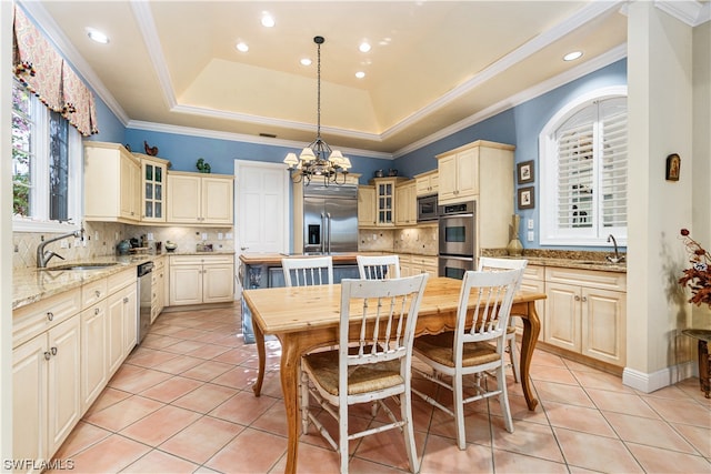 kitchen featuring built in appliances, light stone countertops, light tile patterned floors, pendant lighting, and a tray ceiling