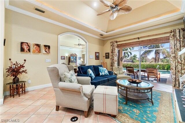 living room featuring ceiling fan, light tile patterned floors, a tray ceiling, and ornamental molding