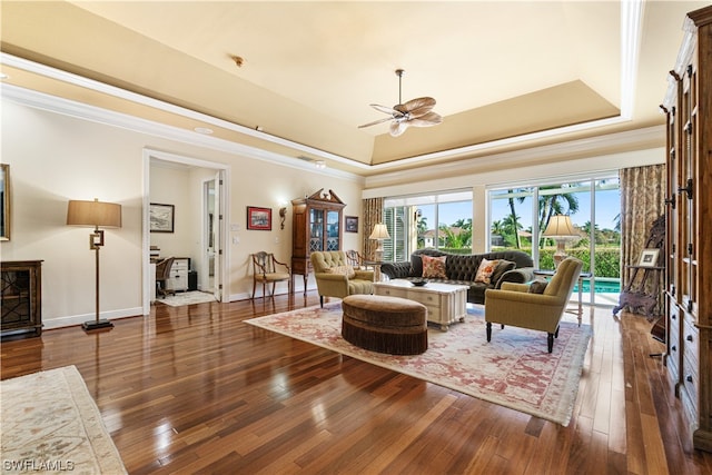 living room featuring ceiling fan, crown molding, dark hardwood / wood-style floors, and a raised ceiling