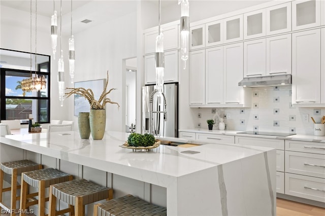 kitchen with pendant lighting, white cabinets, a breakfast bar, and stainless steel refrigerator with ice dispenser