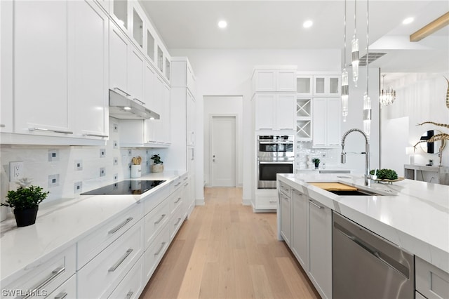 kitchen featuring light hardwood / wood-style flooring, stainless steel appliances, tasteful backsplash, white cabinetry, and sink