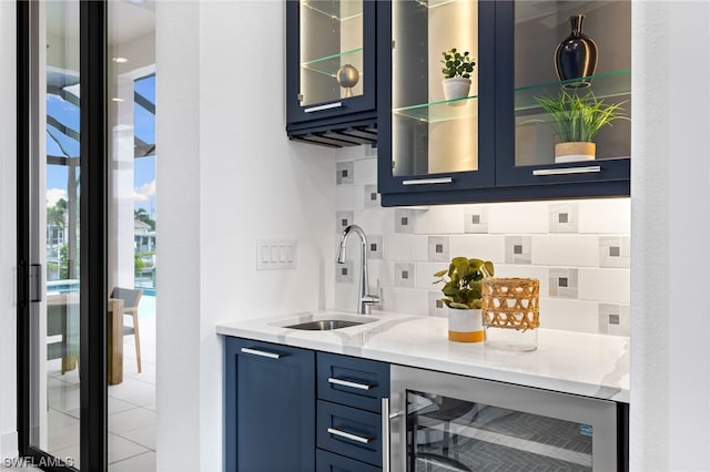 bar featuring light stone counters, wine cooler, sink, backsplash, and blue cabinetry