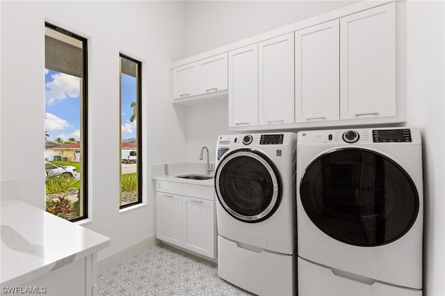 laundry area with washer and clothes dryer, cabinets, sink, and light tile flooring