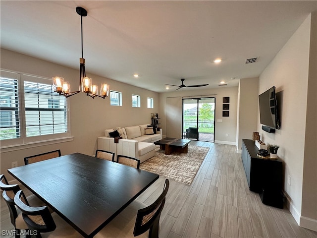 dining room with ceiling fan with notable chandelier and light wood-type flooring