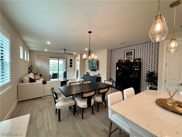 dining area with light hardwood / wood-style floors and ceiling fan with notable chandelier