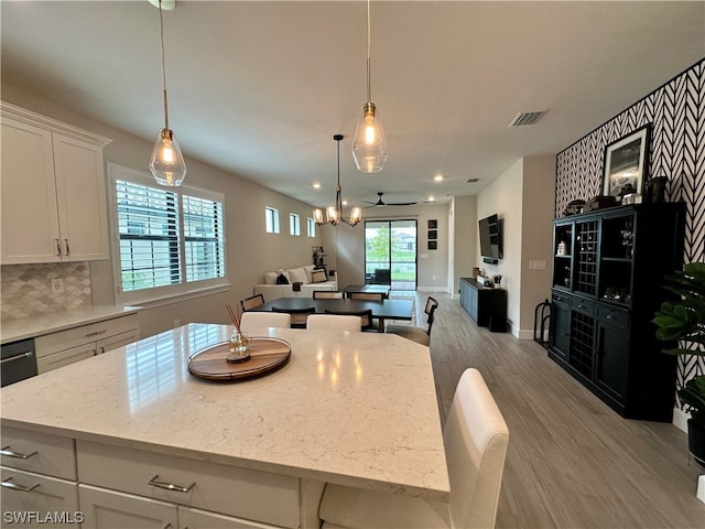 kitchen with hanging light fixtures, white cabinets, and light stone counters