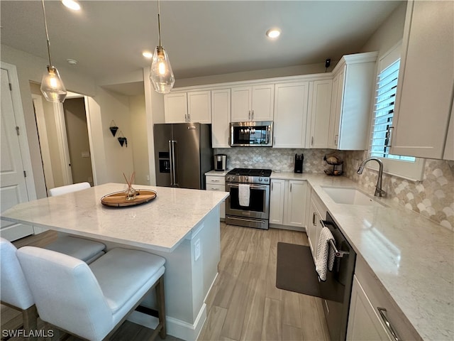 kitchen featuring white cabinets, a breakfast bar area, stainless steel appliances, and light stone counters